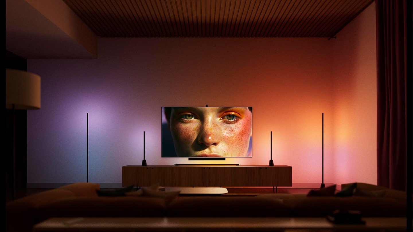 Вітальня з телевізором і світильниками Philips Hue, які світять кольорами картинки на екрані